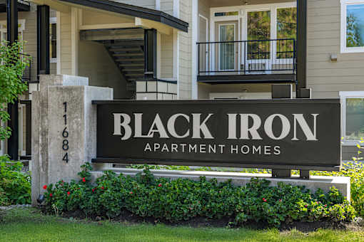 A sign for Black Iron Apartment Homes is in front of a building.