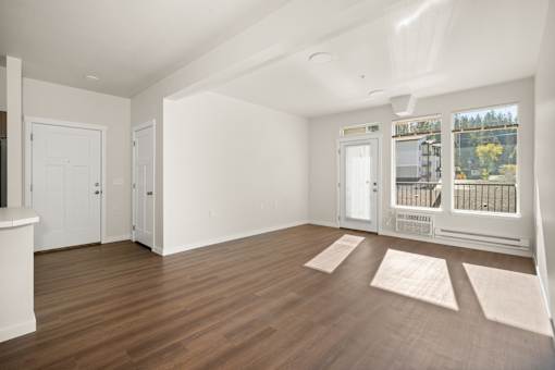 A room with white walls and wooden flooring with a balcony door.