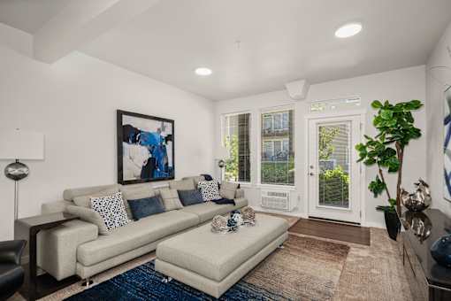 A living room with a couch, a chair, a rug, and a painting on the wall.