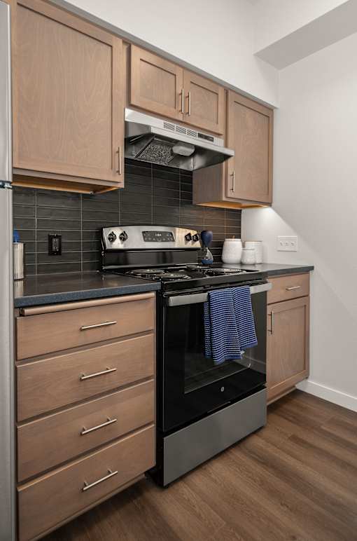 A modern kitchen with wooden cabinets and a black stove top.