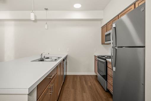 A kitchen with a stainless steel refrigerator and wooden cabinets.