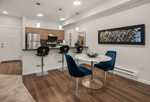 A modern kitchen with a bar area and blue chairs.