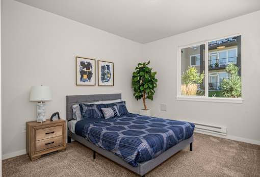 A bedroom with a bed, nightstand, and two pictures on the wall.