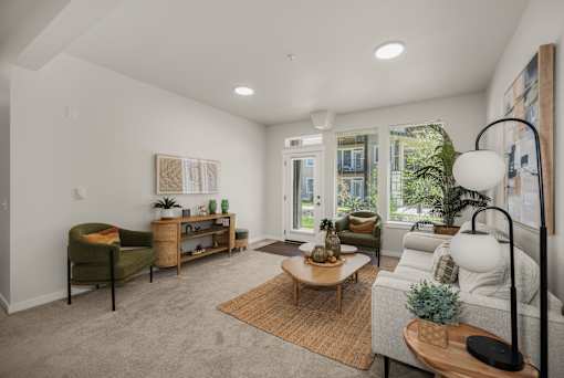 A well-lit living room with a green armchair, a wooden coffee table, and a white sofa.