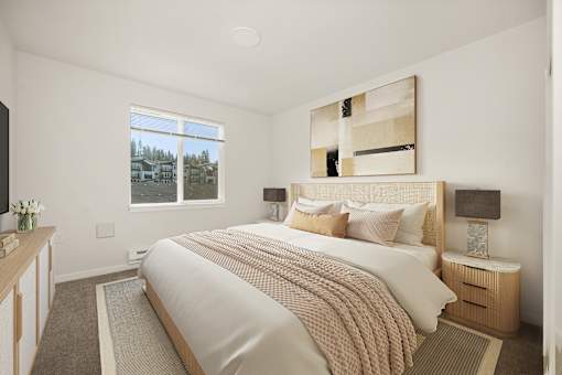 A bedroom with a large bed and a window overlooking a residential area.