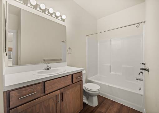 A white bathroom with a toilet, sink, and a glass shower stall.
