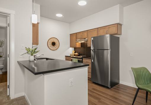 A kitchen with a black countertop and a green chair.
