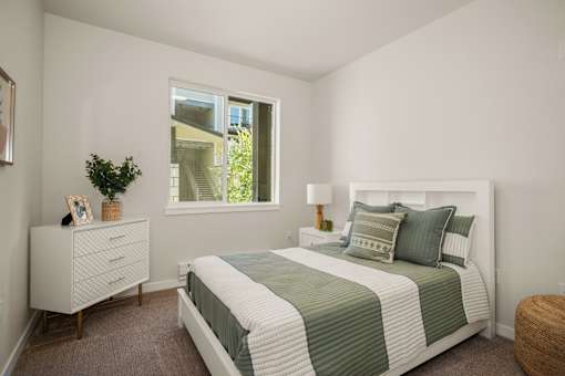 A bedroom with a bed, nightstand, and window.