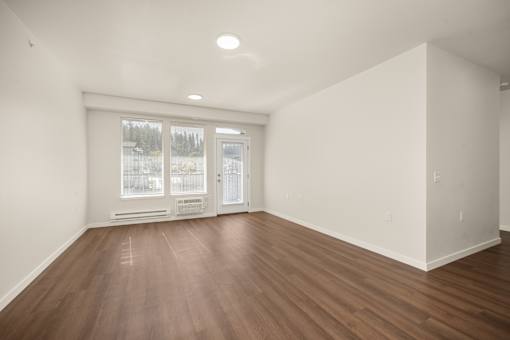 A room with wooden floors and a window overlooking a snowy landscape.