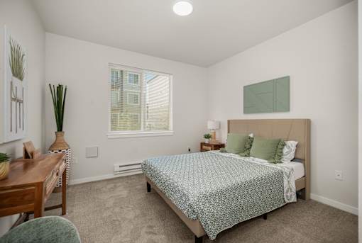 A bedroom with a bed, nightstand, and chair.