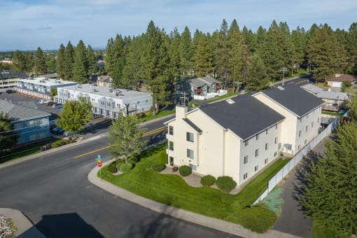 an aerial view of a white building with a street and trees