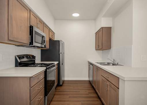 A kitchen with wooden cabinets and a black refrigerator.