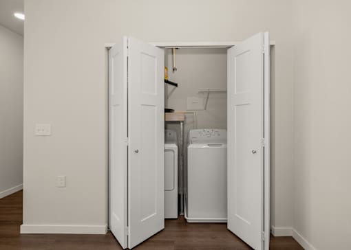 A white door is open to reveal a small laundry room.