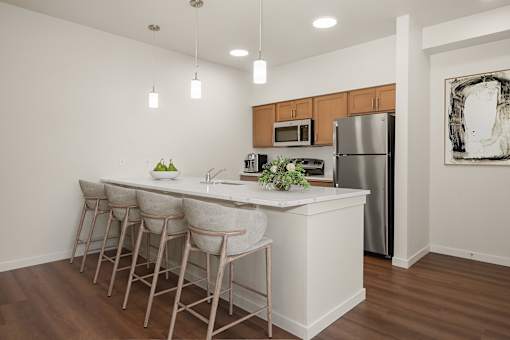 A kitchen with a white island and bar stools.