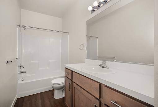 A white bathroom with a toilet, sink, and shower.