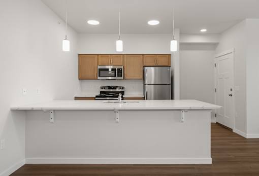A kitchen with white countertops and wooden cabinets.