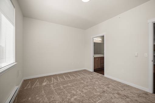 A room with a carpet on the floor and a doorway leading to another room.