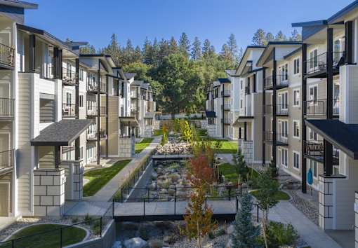 A row of modern townhouses with a small garden in the middle.