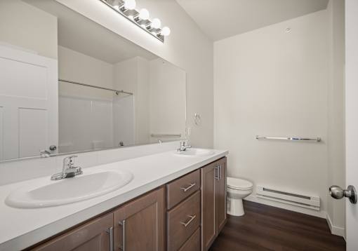 A white sink with a brown cabinet under a mirror in a bathroom.
