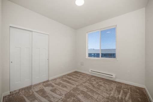A room with a brown carpet and a window overlooking the city.