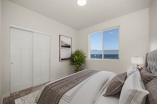 A bedroom with a large bed and a window overlooking the city.
