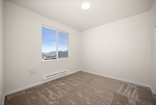 A room with a window and a carpeted floor.