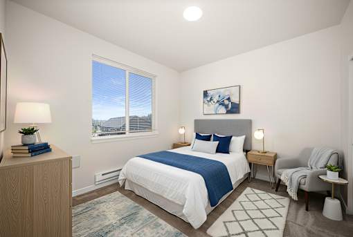 A bedroom with a large bed, a chair, and a window with a view of the outside.