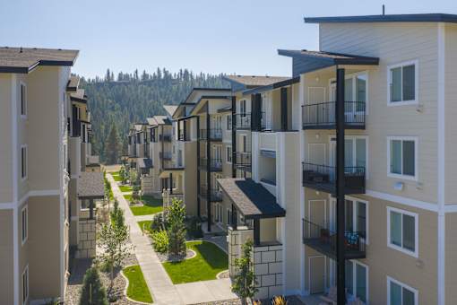 Apartment buildings with balconies line a tree-lined street.