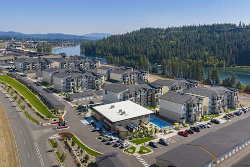 A large building complex with a swimming pool in the foreground and a body of water in the background.