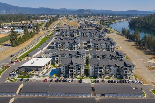 A large residential complex with a lake and mountains in the background.