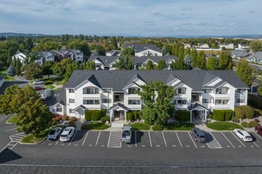 an aerial view of an apartment complex with cars parked in a parking lot