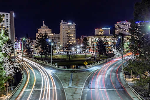 A nighttime cityscape with a curved road and multiple lanes.