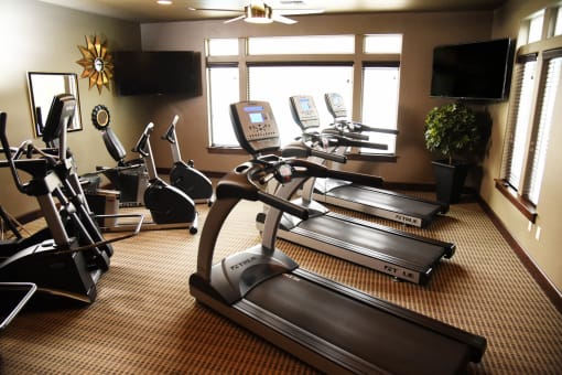 a gym with treadmills and televisions