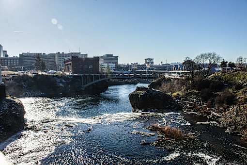 A river flows through a rocky landscape with buildings in the background.
