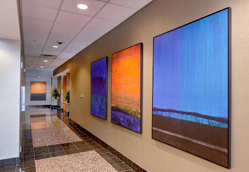 Three paintings hang on a wall in a hallway.