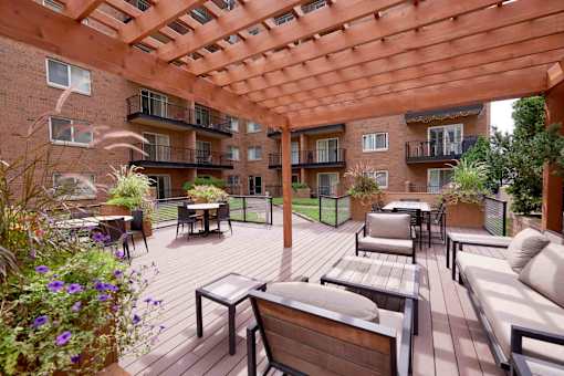 A wooden patio with a pergola and furniture.
