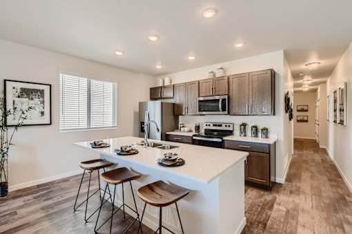 modern kitchen with island and stools in front of stainless steel appliances