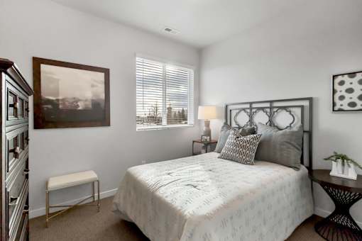 A bedroom with a large bed, a small table, and a painting on the wall.