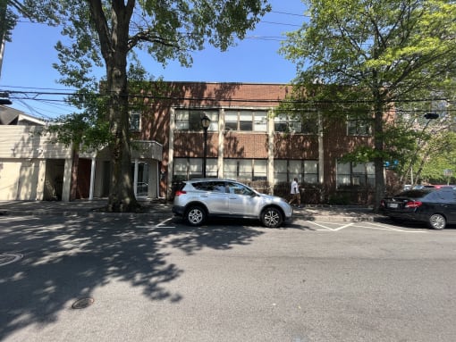 a large brick building with a red roof and a white car parked in front of it