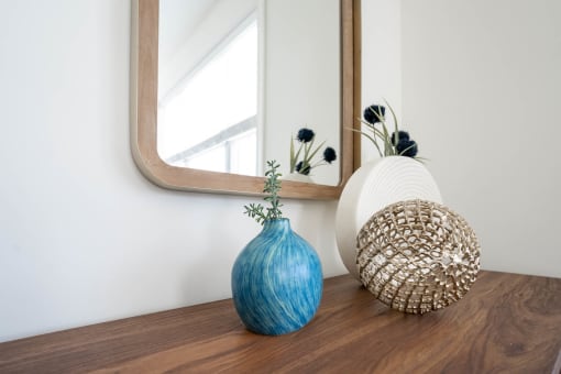 a vase and a basket on a table in front of a mirror