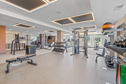 a spacious fitness room with cardio equipment and weights