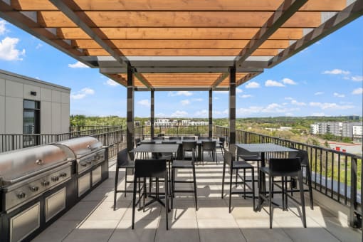 a patio with tables and chairs and a grill