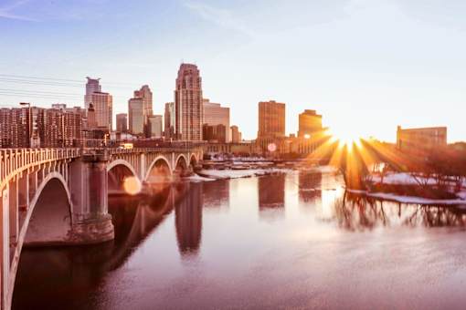 A bridge over a river with a city skyline in the background.