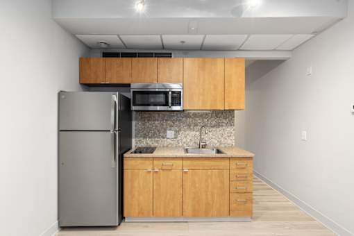 A kitchen with a refrigerator, microwave, and sink.
