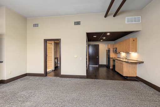 A spacious room with a kitchen area and a carpeted floor.