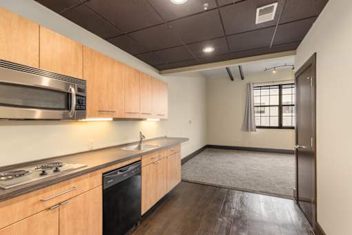 A kitchen with wooden cabinets and a black dishwasher.