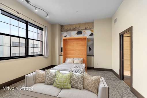 A bedroom with a large bed and a window with blinds.
