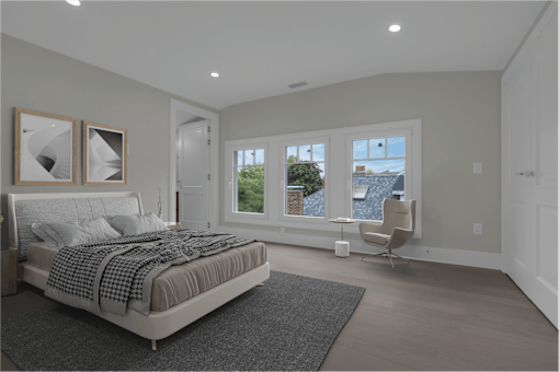 a bedroom with a bed and a chair in front of three windows