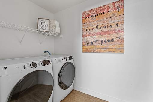 a washer and dryer in a laundry room with a painting on the wall