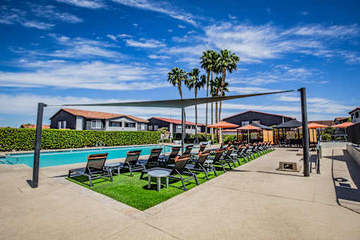A poolside area with lounge chairs and a shade sail.